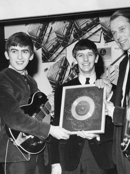 George Martin (2.v.r.) zusammen mit den Beatles bei der Übergabe einer Silbernen Schallplatte (für eine viertel Million verkaufte Alben) in London im Jahre 1963.