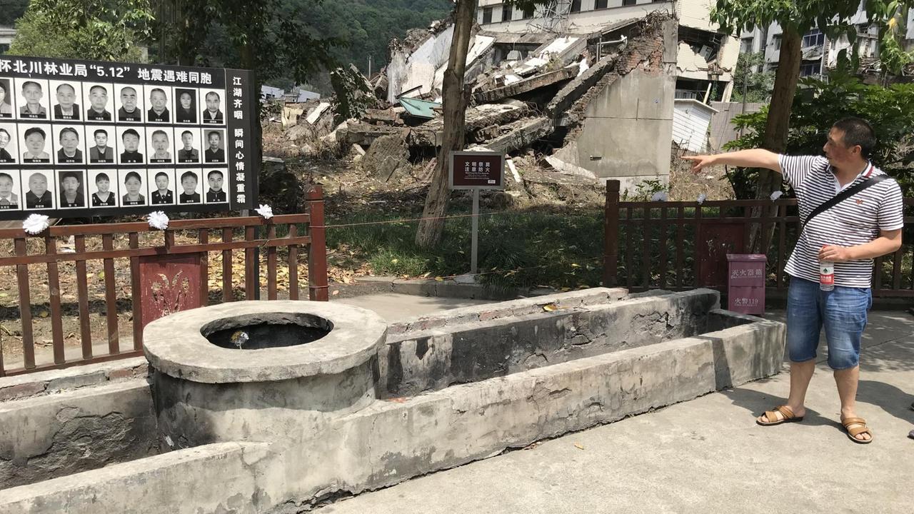 Der Überlebende Lù Táo zeigt auf eine Gedenktafel im zerstörten Běichuān