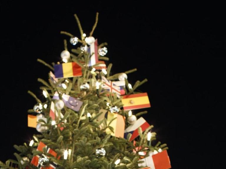 Ein Weihnachtsbaum voller Flaggen vieler Länder am Checkpoint Charly in Berlin.