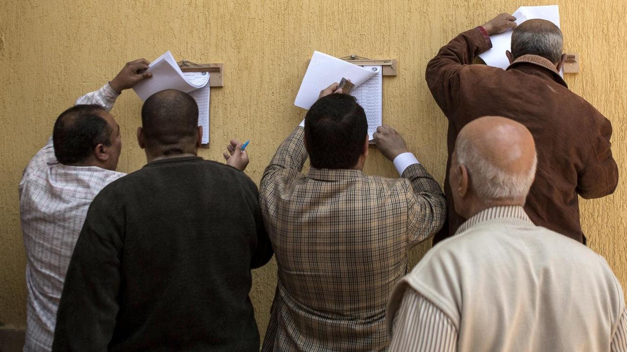 Männer suchen in einer Liste nach ihrem Wahllokal, um am ersten Tag des Referendums über neue Machtbefugnisse für Ägyptens Präsident Al-Sisi abzustimmen.