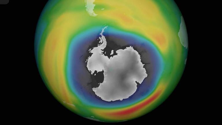 Ein Globus im schwarzen All, der an unterschiedlich bunt eingefärbt ist und in der Mitte eine graue Fläche zeigt: das Ozonloch über der Antarktis.