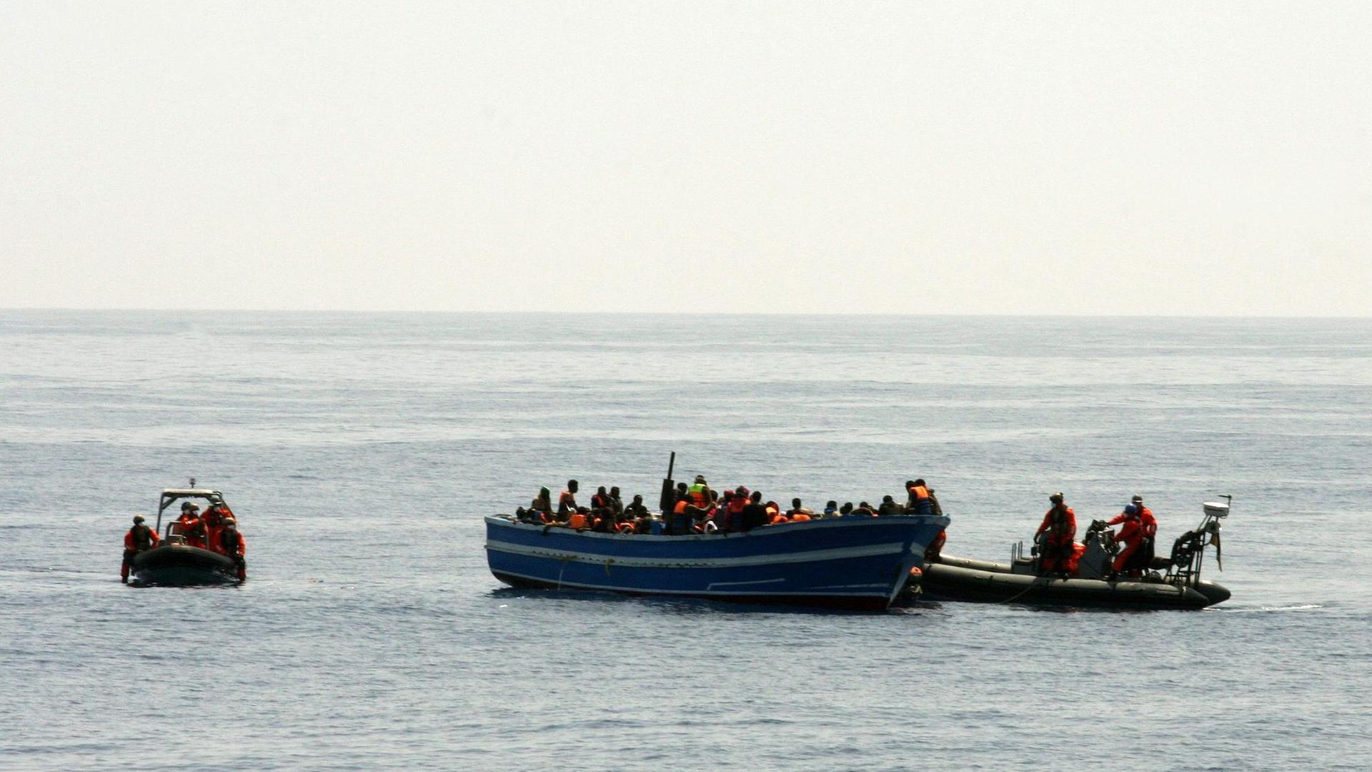 Bundeswehrsoldaten bergen von zwei kleinen Motorbooten aus am 08.05.2015 im Mittelmeer schiffbrüchige Flüchtlinge. In der Mitte ist das Holzboot zu sehen, das zu kentern droht. 