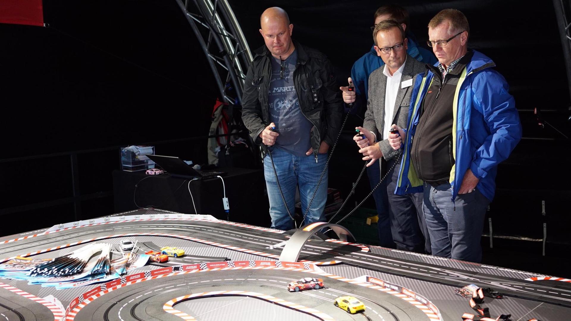 Männer spielen an einer Carrera-Bahn Männer spielen an einer Carrera-Bahn