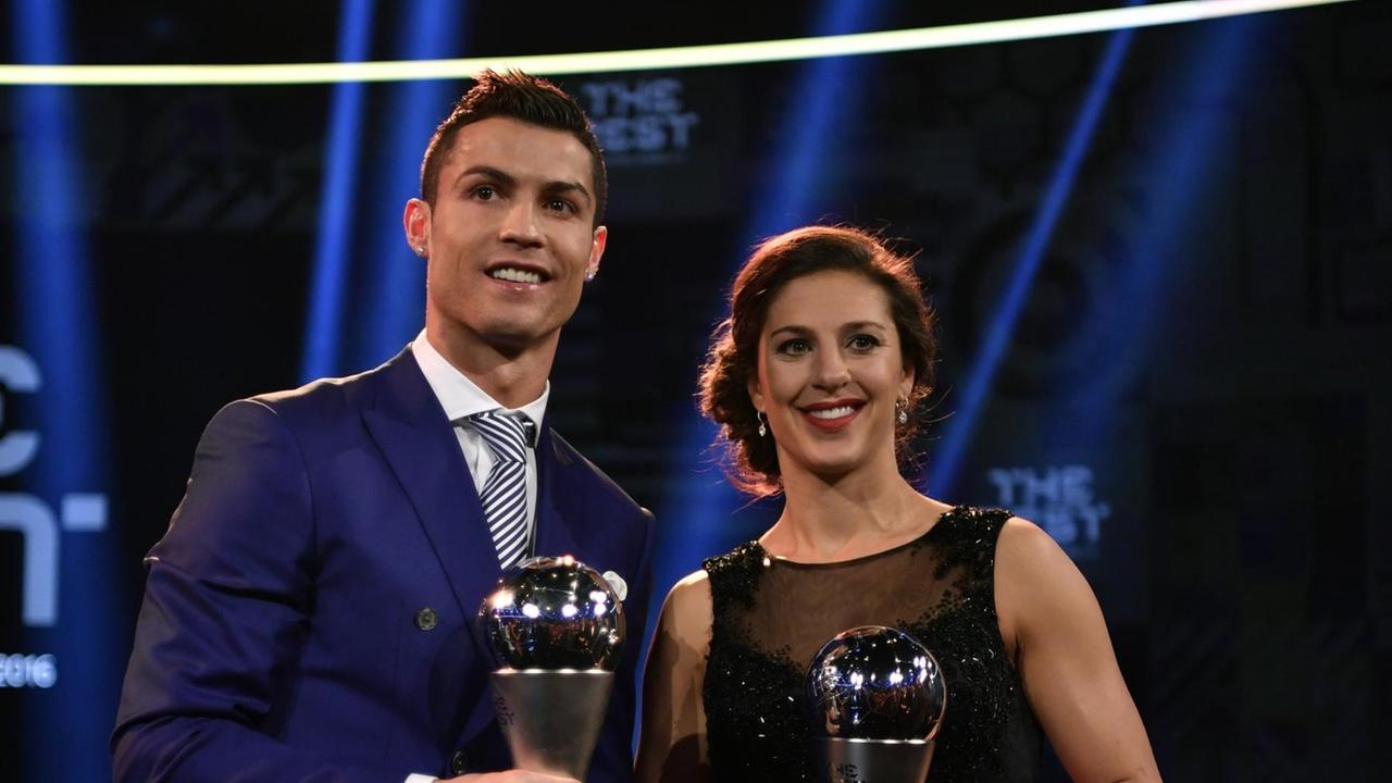 Ronaldo und Lloyd stehen gemeinsam auf der Bühne und zeigen ihre Pokale.