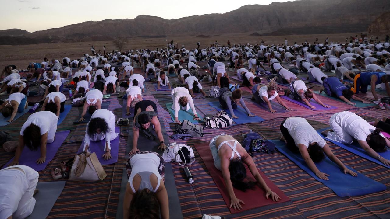 Menschen üben in der Arava Wüste in Israel Yoga.