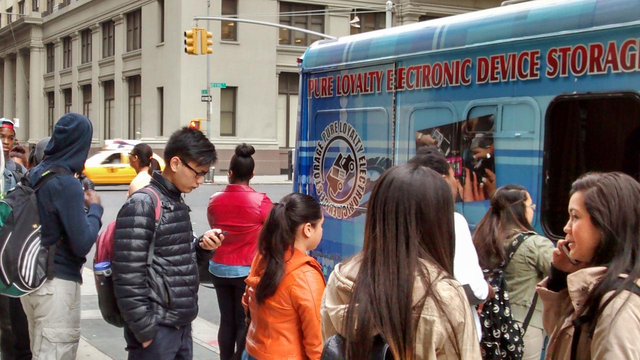 Schüler geben vor einer Schule in New York City ihre Telefone ab.