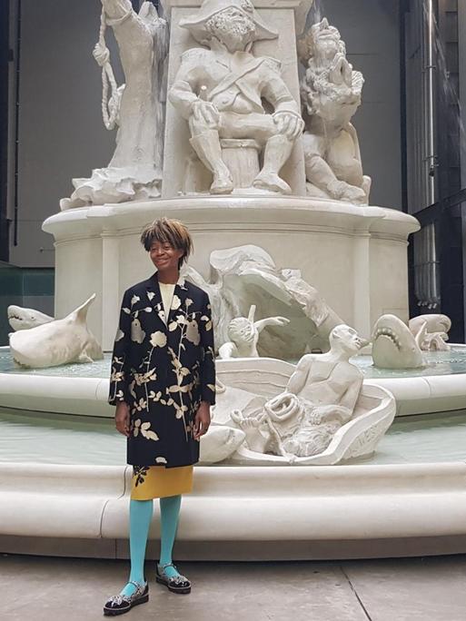 Die US-Künstlerin Kara Walker steht vor einem riesigen, mehrstufigen weißen Brunnen in der Londoner Tate Modern Galerie.