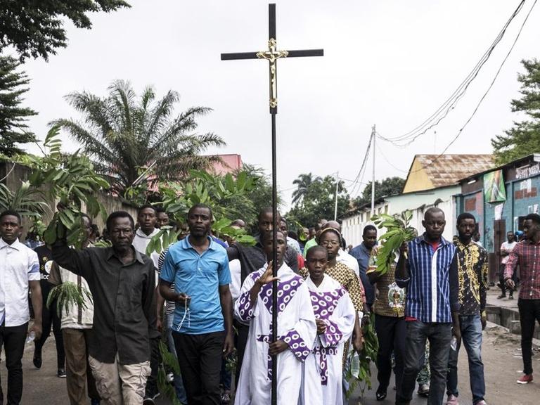 Kirchennahe Demonstranten in der Demokratischen Republik Kongo protestieren gegen Präsident Kabila. Ein Mann in der Mitte der Gruppe trägt ein großes Kreuz.