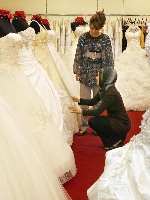Eine Verkäuferin zeigt ihrer Kundin eine Auswahl an Hochzeitskleidern im Duisburger Stadtteil Marxloh bei "Prestije".