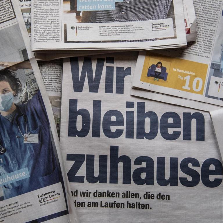 Zeitungen mit Anzeigen zur Corona-Ausbreitung unter dem Motto "Wir bleiben zuhause"
