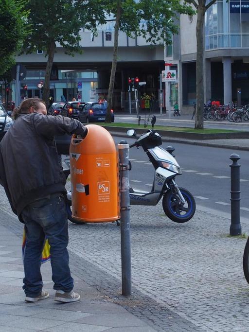 Ein Mann greift im auf der Schloßstraße im Bezirk Steglitz/Zehlendorf in Berlin am 15.06.2014 in einen Papierkorb, um an eine Pfandflasche zu kommen.