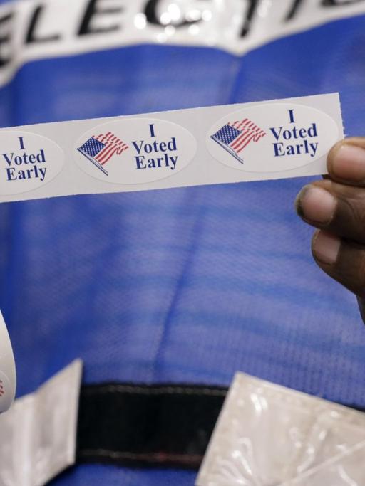 Zwei Hände halten eine Rolle mit Aufklebern mit der Aufschrift "I voted early".