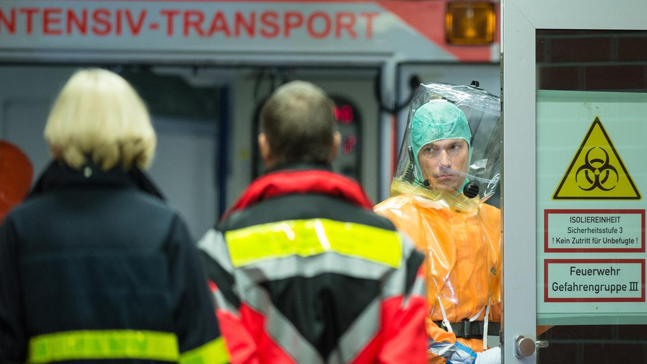 Ein an Ebola erkrankter Patient wird mit einem speziellen Krankenwagen zur Isolierstation der Uniklinik in Frankfurt am Main (Hessen) gebracht. Feuerwehrleute und Ärzte in Schutzanzügen begleiten die Ankunft des Mannes.