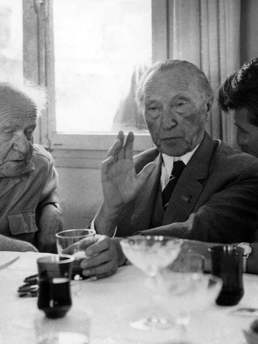 David Ben Gurion (l), der ehemalige israelische Premierminister, Bundeskanzler Konrad Adenauer (M) und ein Dolmetscher (r) am 09.05.1966 im Kibbuz Sede Bokar nach dem Mittagessen im Gespräch. Adenauer besuchte das Kibbuz während seines Staatsbesuches in Israel und bekam von Ben Gurion dessen neustes, in Großbritannien erschienenes Buch "The Jews in Their Land" mit einer persönlichen Widmung geschenkt.