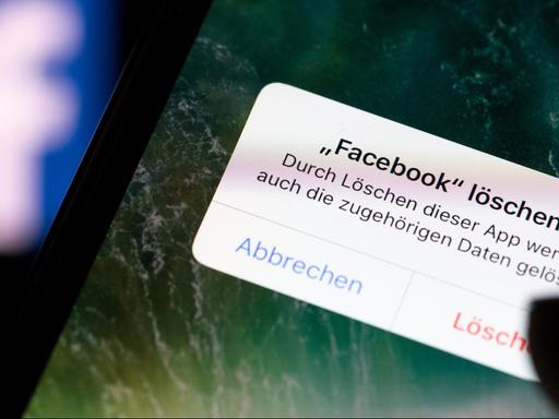 Auf dem Bildschirm eines Smartphones steht vor dem Logo der Facebook-App der Dialog "Facebook löschen?"