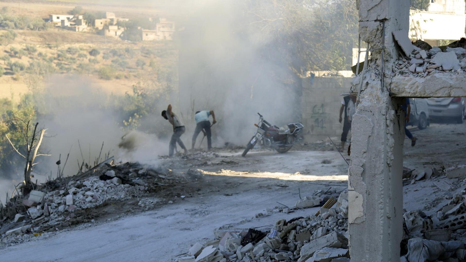 Syrer versuchen einen Brand nach einem Luftangriff im Bezirk Jisr al-Shughur in der Provinz Idlib zu löschen.