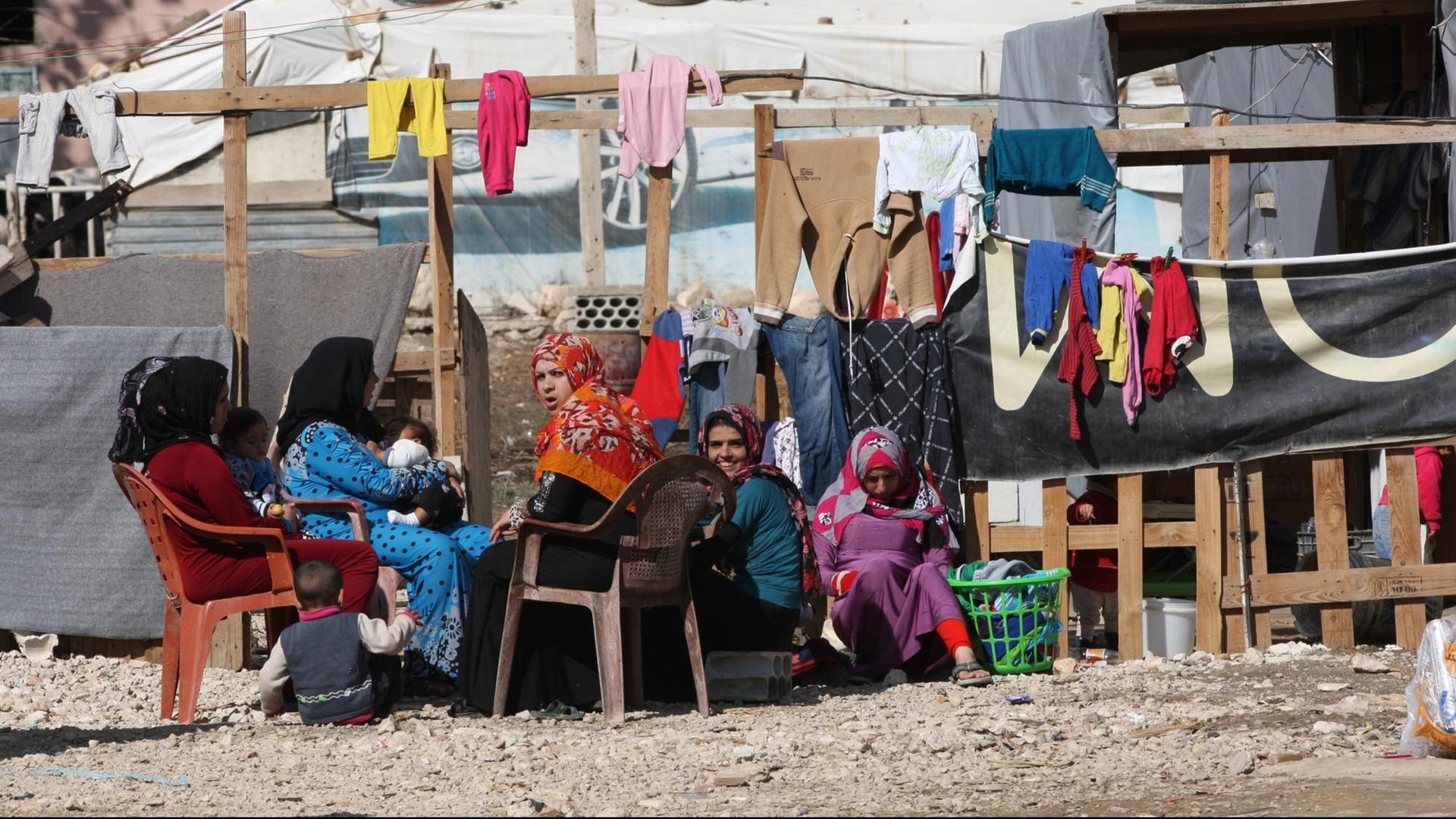 Frauen sitzen im Libanon in der Bekaa-Ebene in einem Flüchtlingslager vor ihren Behausungen.
