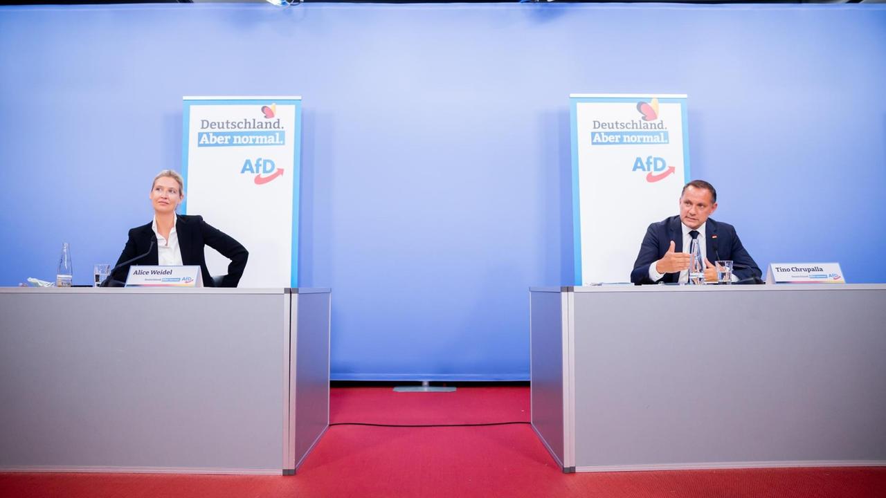 Die AfD-Spitzenkandidaten Alice Weidel (l) und Tino Chrupalla (r) bei der Vorstellung ihrer Kampagne zur Bundestagswahl in Berlin. Sie sitzen in großem Abstand zueinander auf einem Podium. An der Wand Plakate mit der Aufschrift "Deutschland. Aber normal".
