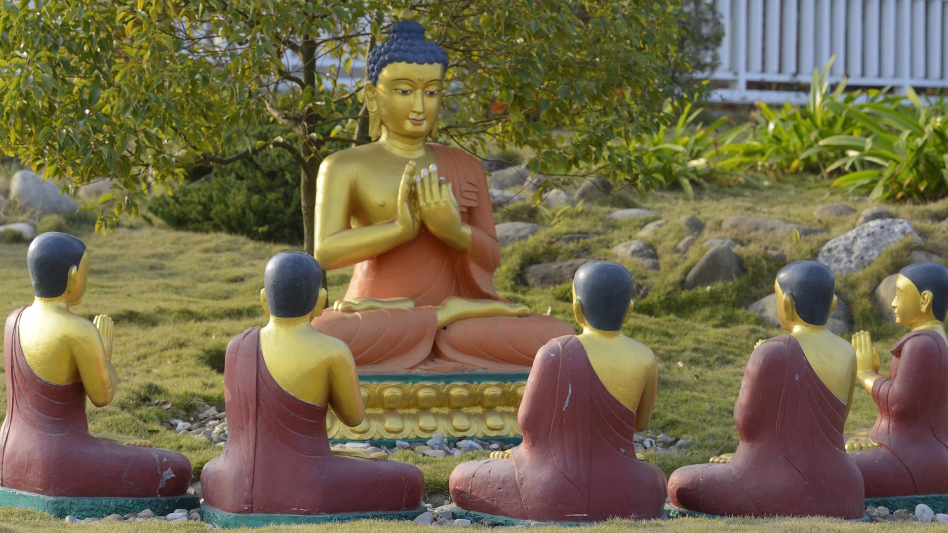 Denkmal vom sitzenden Buddha mit seinen Juengern im Tempel Karma Kagyo Monastery im Heiligen Garten von Lumbini - dem Geburtsort von Siddhartha Gautama, den wir unter der Bezeichnung Buddha kennen.