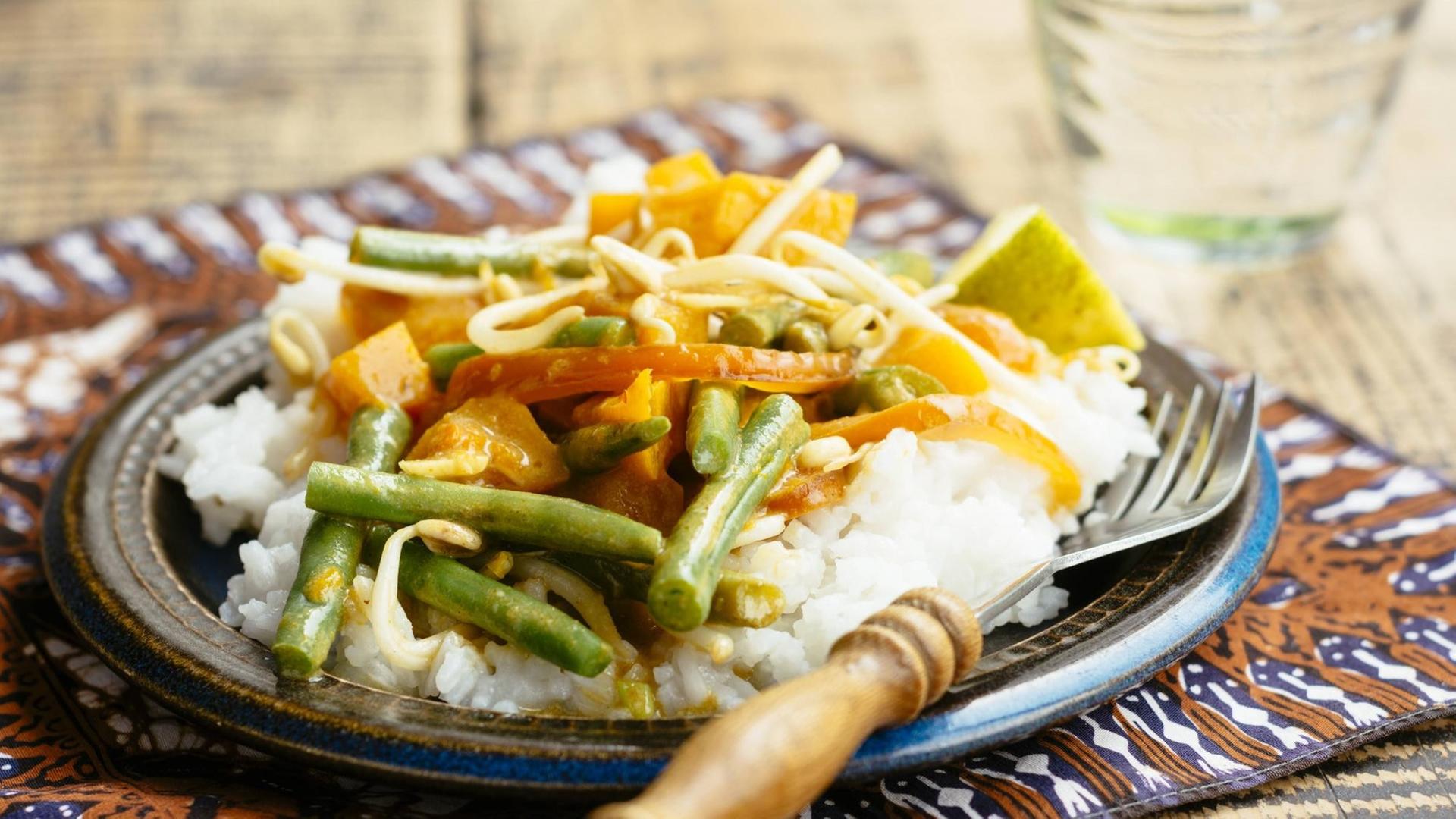 Thai Curry mit Kürbissen und grünen Bohnen auf einem Teller.