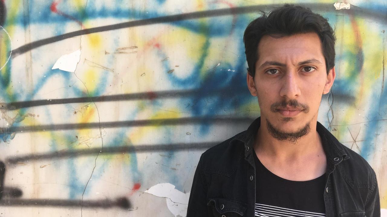 Zaid Saad, einer der Organisatoren des Tarkib-Festivals für zeitgenössische Kunst in Bagdad, steht vor einer Graffitti-Wand