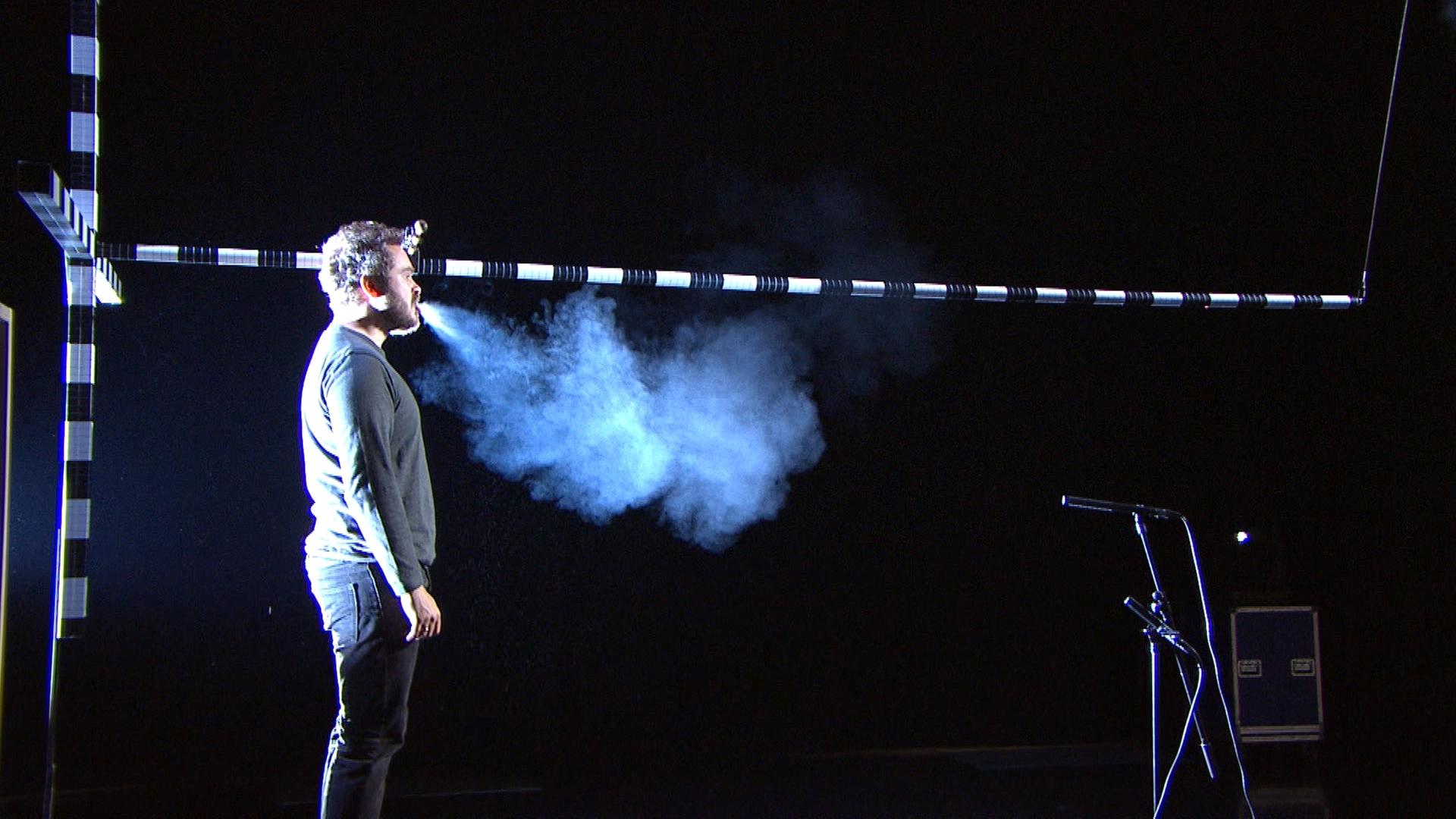 Ein Sänger stößt beim Singen eine Aerosol-Wolke aus.