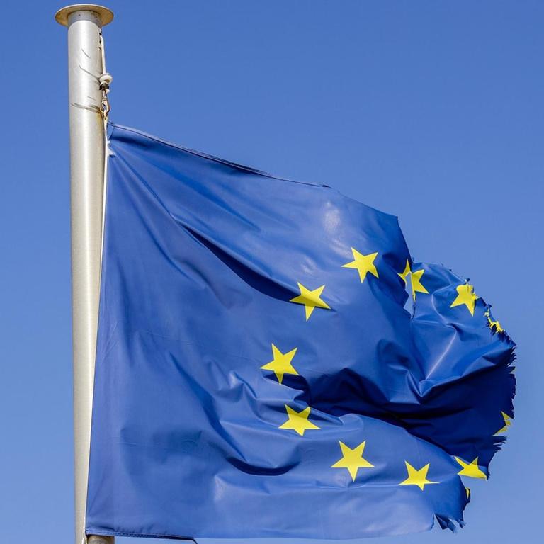 Eine zerrissene EU-Fahne flattert am Fahnenmast.