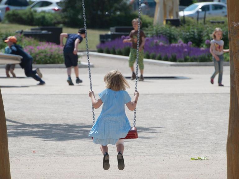 Ein Mädchen sitzt auf einem Spielplatz in Erfurt (Thüringen) auf einer Schaukel.