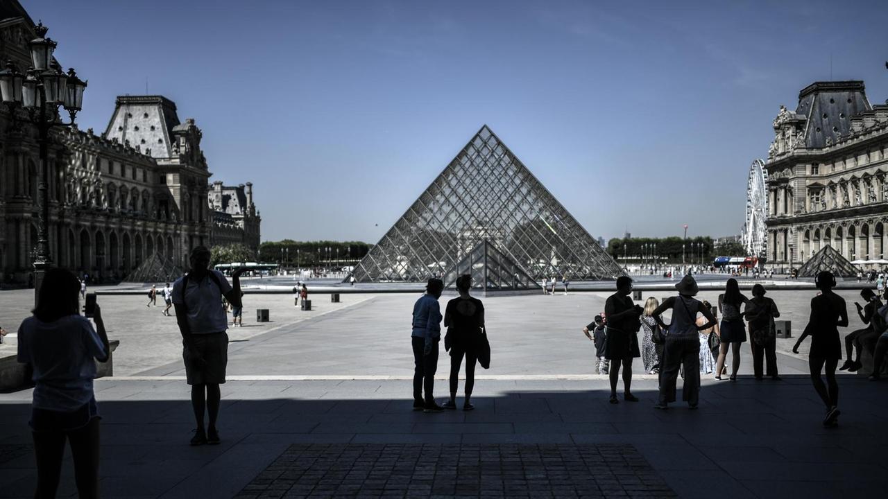 Das Foto zeigt Touristen am Louvre in Paris mit der Pyramide am 6. August 2020.