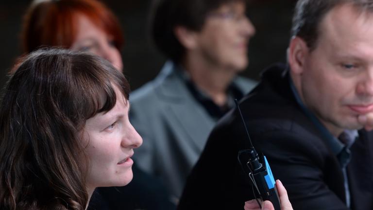 Neben dem Intendanten des Schauspiels Leipzig, Enrico Lübbe (r), erläutert Anke Nicolai von der Firma audioskript am 30.10.2013 auf einer Pressekonferenz in Leipzig (Sachsen) die Umsetzung von Theater für sehbehinderte Menschen und hat dabei ihr Baby auf 