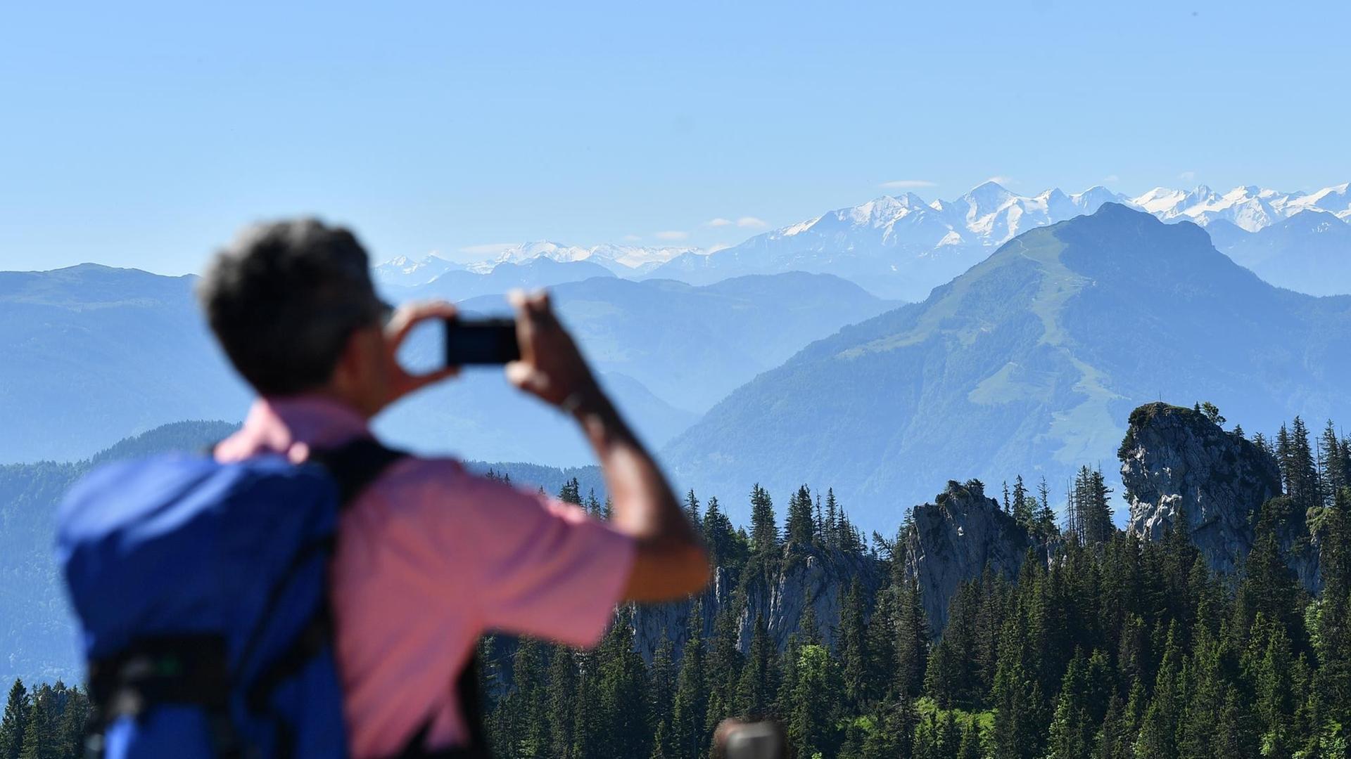 Ein Wanderer fotografiert Berge in den bayerischen Alpen