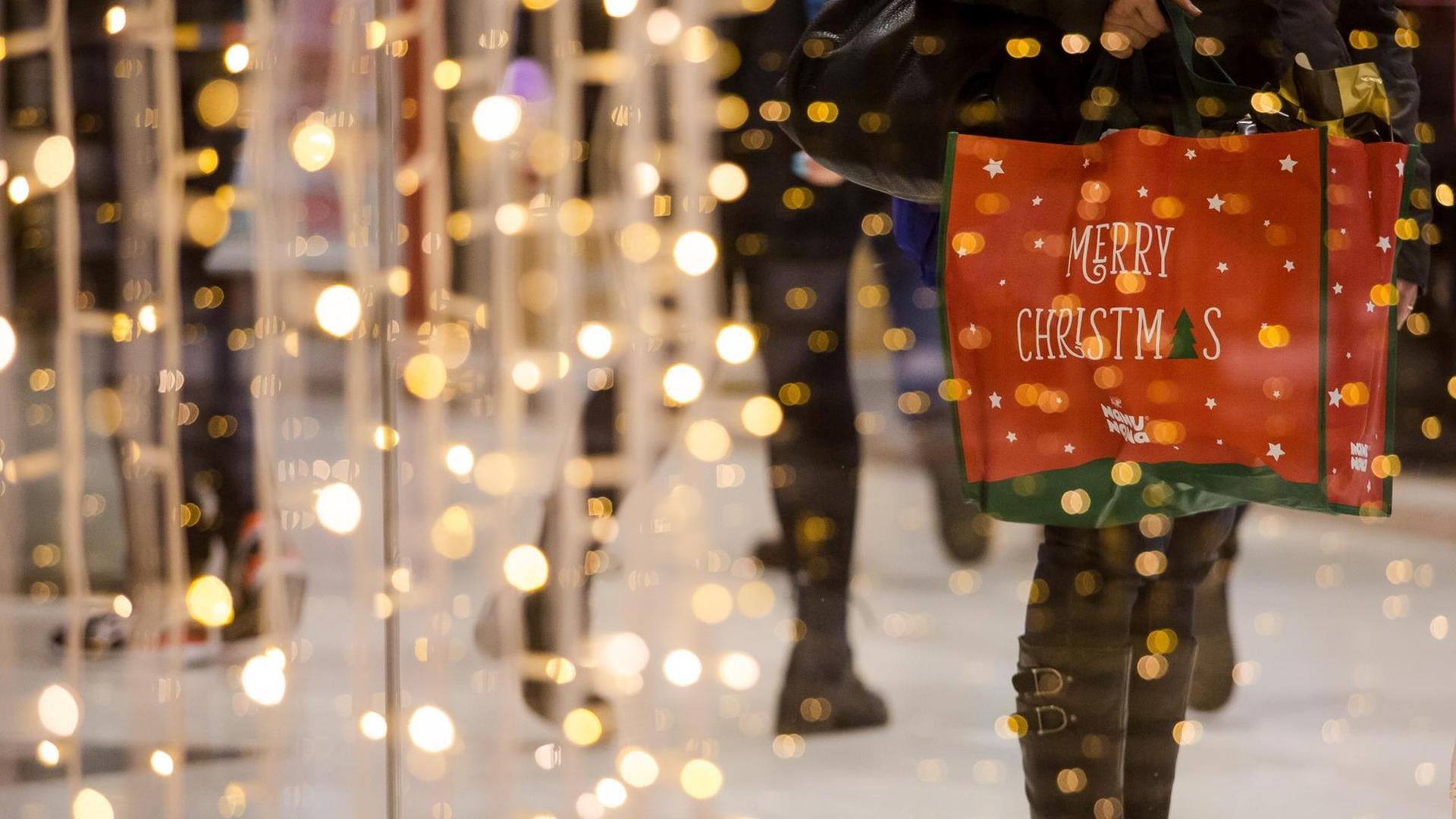 Eine Frau steht am 10.12.2016 mit einer weihnachtlichen Einkaufstüte in einem Kaufhaus in Stuttgart (Baden-Württemberg). Dutzende Menschen nutzten den Samstag für Einkäufe in der Stuttgarter Innenstadt.