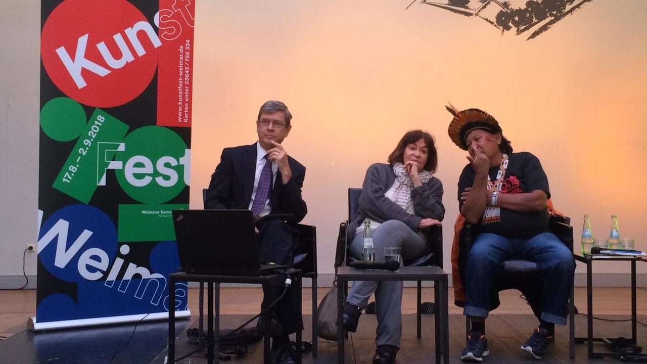 Der Anthropologe Stephen Corry, die Fotografin Claudia Andujar und der Schamane Davi Kopenawa bei ihrem Auftritt beim Kunstfest Weimar 2018 (v.li.). Der Anthropologe Stephen Corry, die Fotografin Claudia Andujar und der Schamane Davi Kopenawa bei ihrem Auftritt beim Kunstfest Weimar 2018 (v.li.).