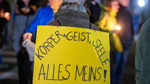 Teilnehmerin einer Demonstration gegen die Corona-Beschränkungen in Schwerin. Ein Protestschild auf dem Rücken:"Körper, Geist und Seele, alles meins!"