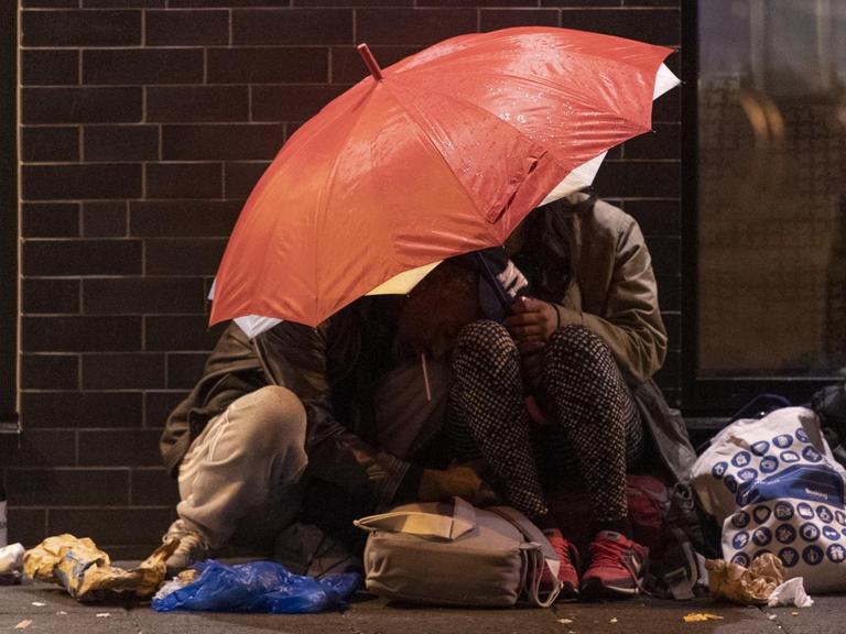 Zwei Menschen haben sich am Rande der Veranstaltung "Bahnhofsviertelnacht" in Frankfurt am Main unter einen Regenschirm zurückgezogen.