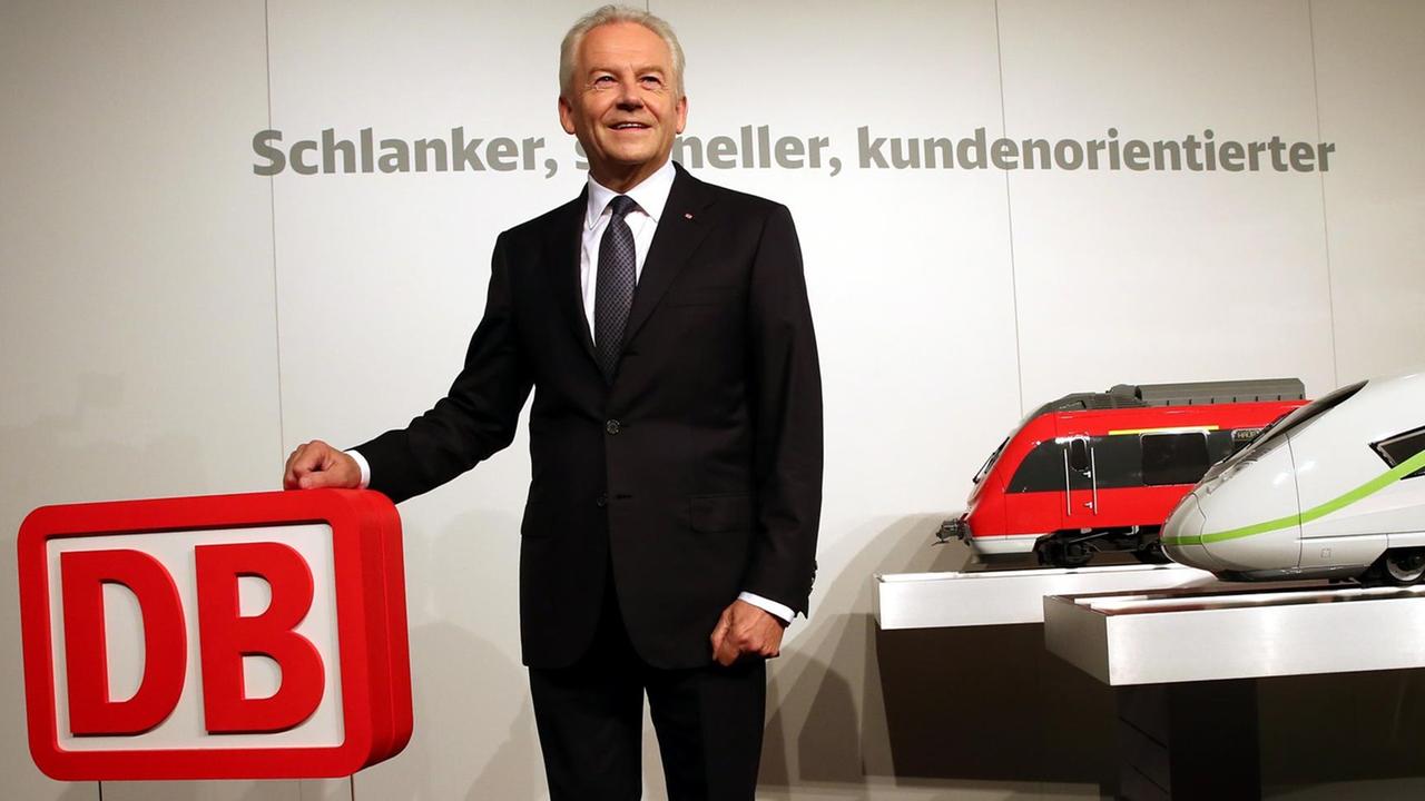 Bahnchef Rüdiger Grube posiert zu Beginn der Halbjahres-Pk für die Fotografen. Er hält die Hand auf ein Bahn-Logo. Neben ihm sind zwei große Modellbahnen zu sehen.