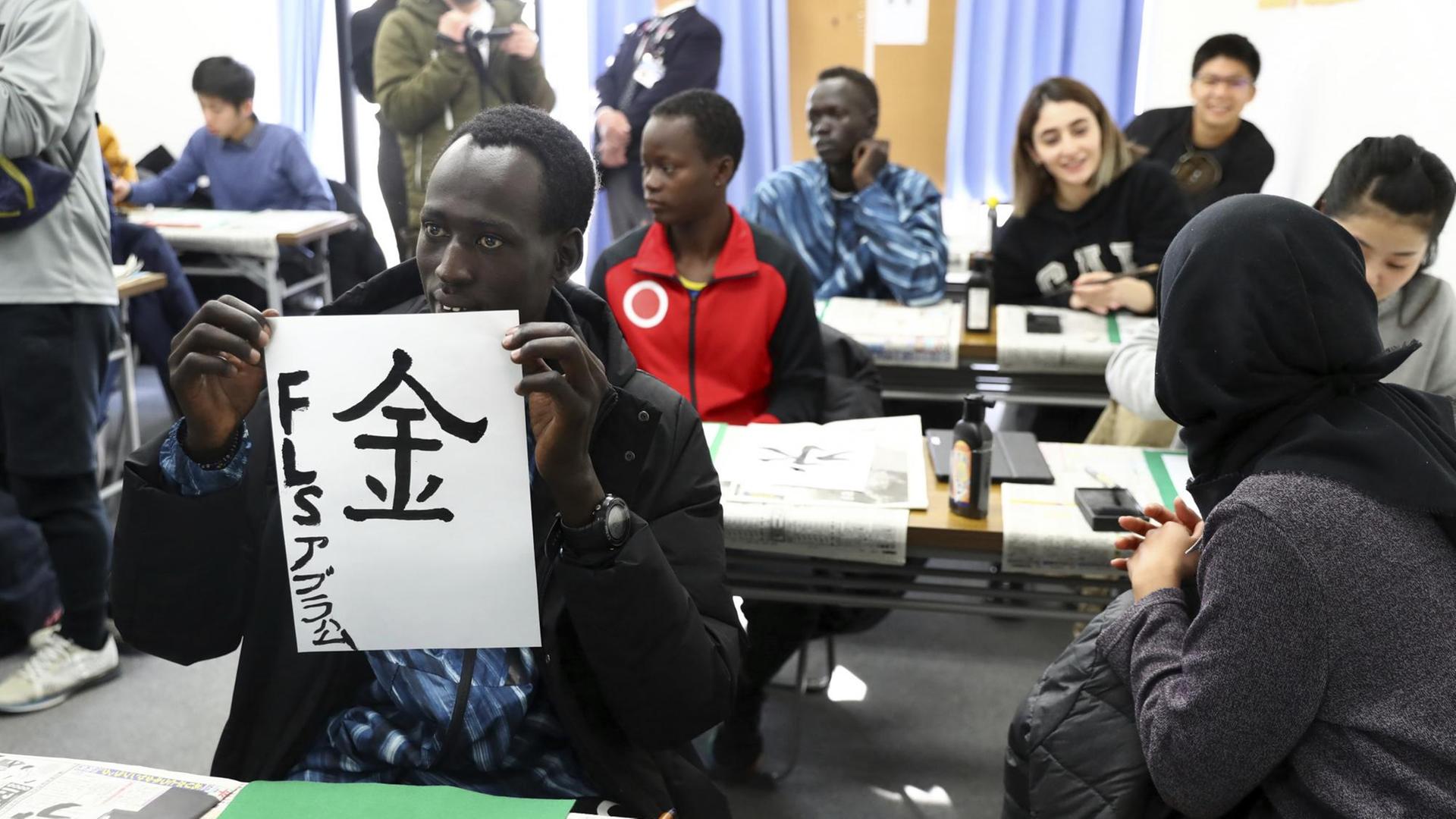 Die südsudanesischen Athleten und Athletinnen üben japanische Schriftzeichen.