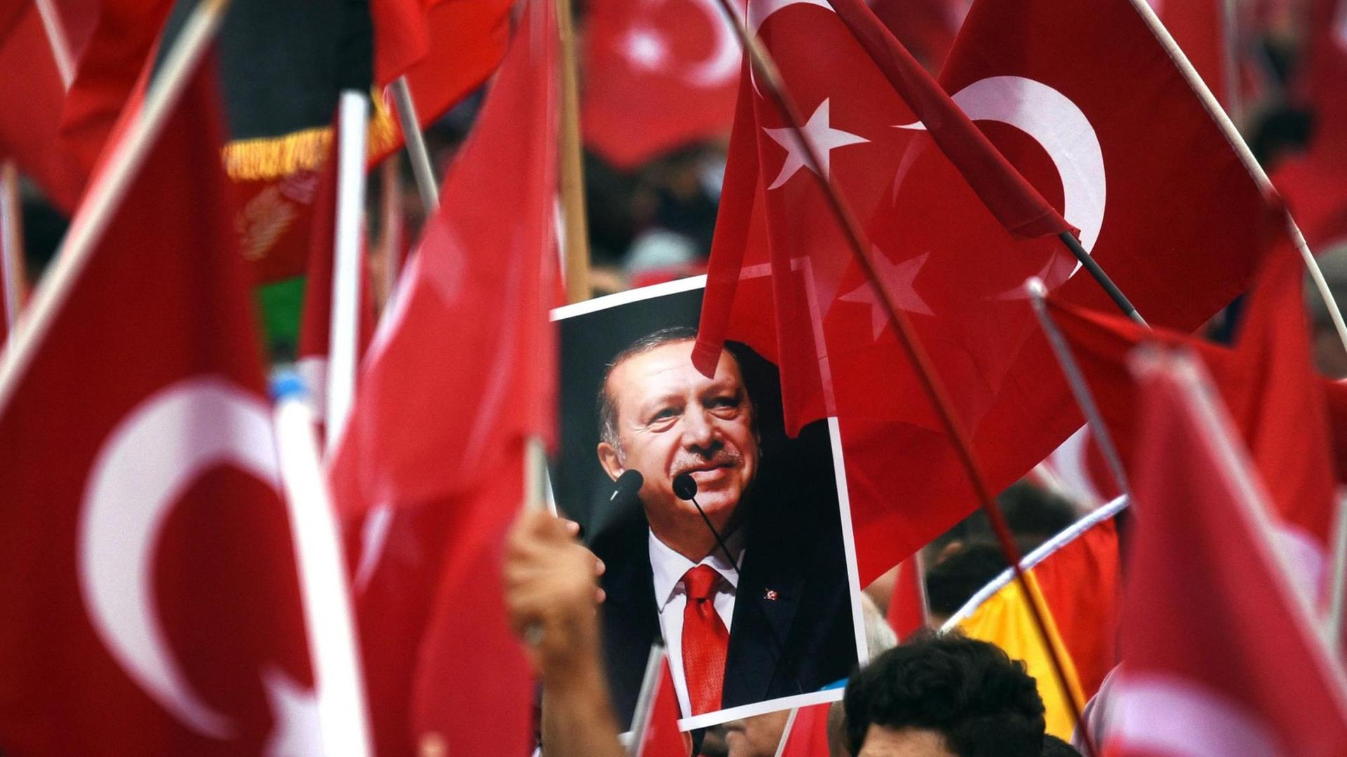 Anhänger des türkischen Staatspräsidenten Recep Tayyip Erdogan halten in Köln Fahnen und ein Bild des Staatschefs.