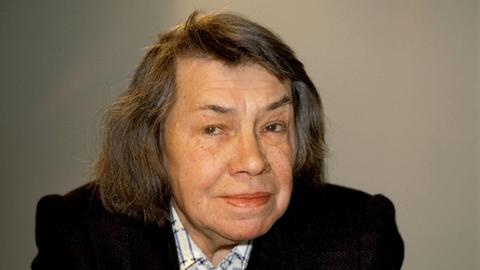 Ein Farbfoto zeigt Patricia Highsmith freundlich die Kamera blickend