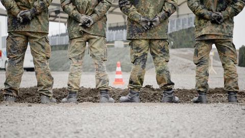Rückansicht von Soldaten der Bundeswehr. Sie stehen in Uniform nebeneinander und falten die Hände hinter dem Rücken.