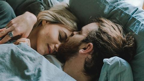 Ein Mann und eine Frau liegen im Bett und umarmen sich.
