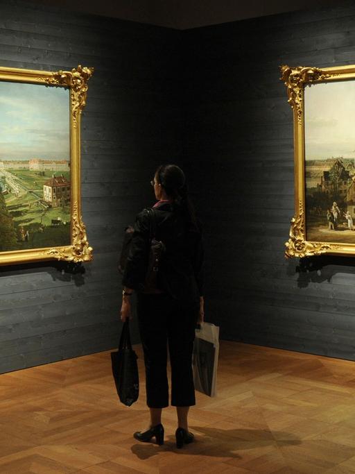 Eine Besucherin betrachtet in München in der Alten Pinakothek in der Ausstellung «Canaletto. Bernardo Bellotto malt Europa» die Bilder "Das Schloss Nymphenburg von der Stadtseite" (l, München 1761) und "München von Osten" (r, 1761).