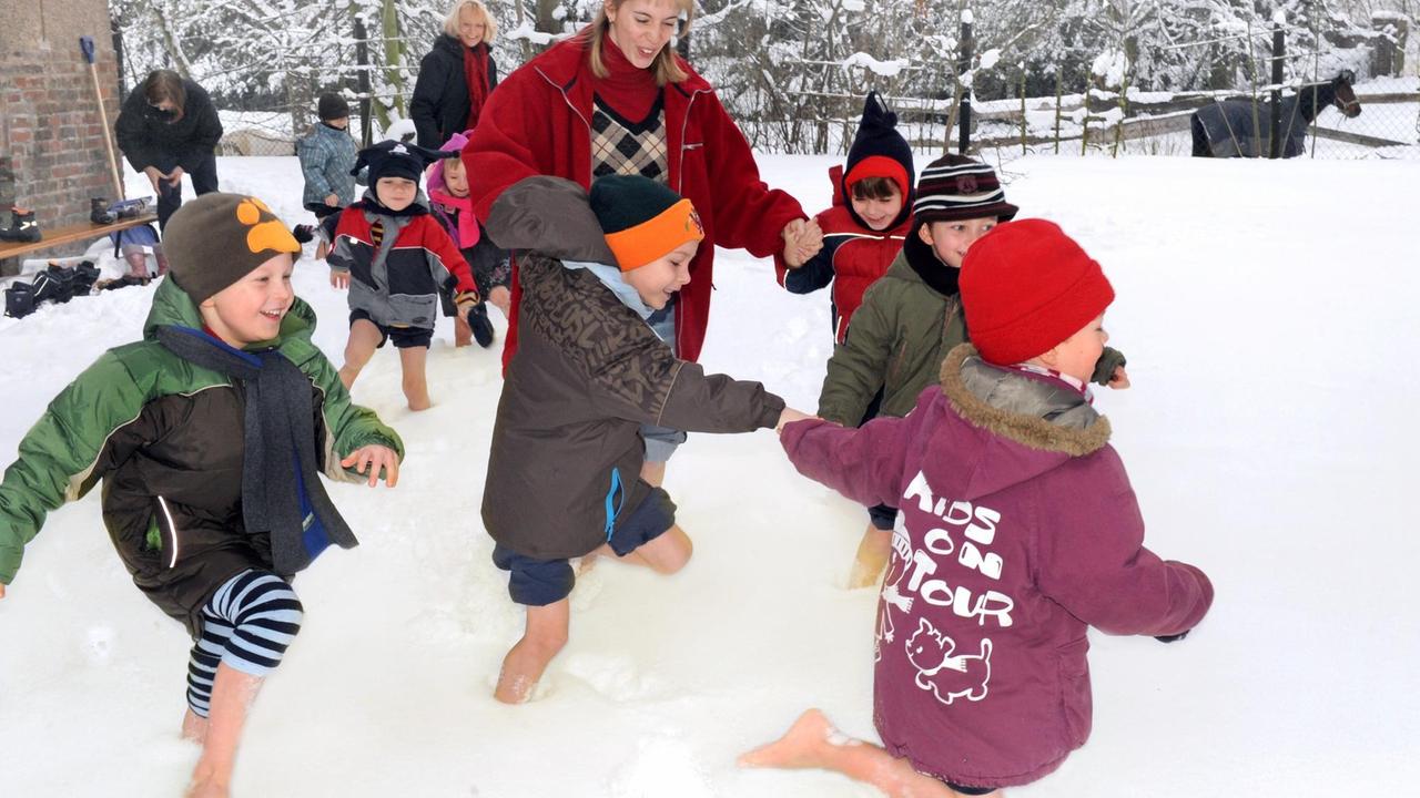 Kinder des Kneipp- und Naturkindergartens "Gänseblümchen" laufen in Mücheln in Sachsen-Anhalt gemeinsam mit Erzieherinnen beim Abhärtungsprogramm barfuß durch den Schnee.