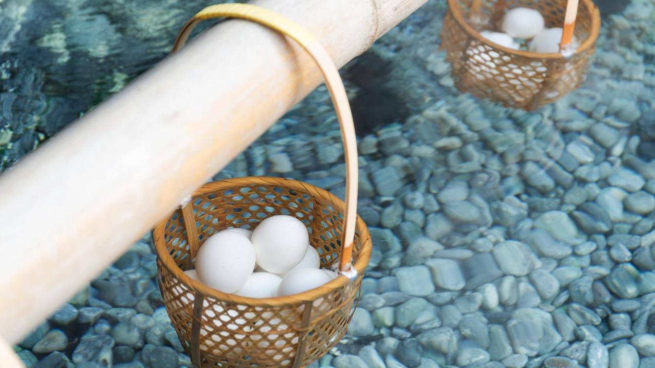 Mehrere Eier liegen in einem Korb im Wasser einer heißen japanischen Quelle. Man nennt so zubereitete Eier Onsen Eier. Mehrere Eier liegen in einem Korb im Wasser einer heißen japanischen Quelle. Man nennt so zubereitete Eier Onsen Eier.