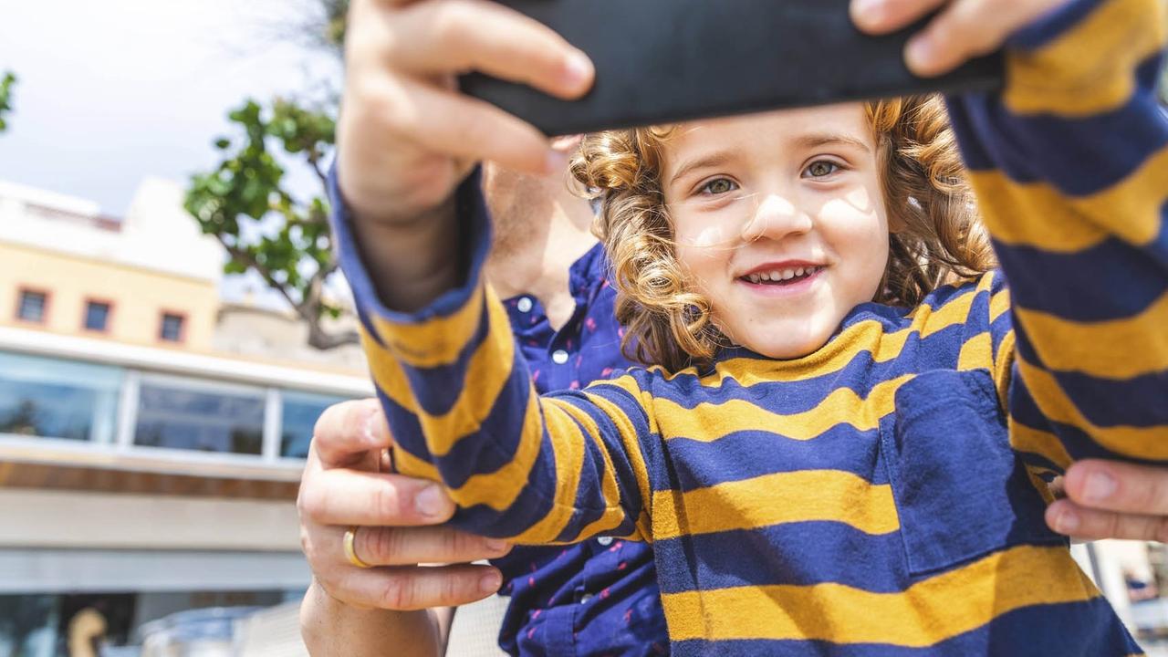 Ein Kind macht ein Selfie von sich und seinem Vater.