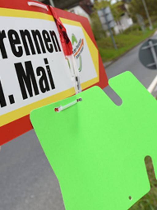 Ein Wegweiser mit der Aufschrift "Radrennen 1. Mai" ist an einem Kreisel in Oberursel an einem Pfosten befestigt.