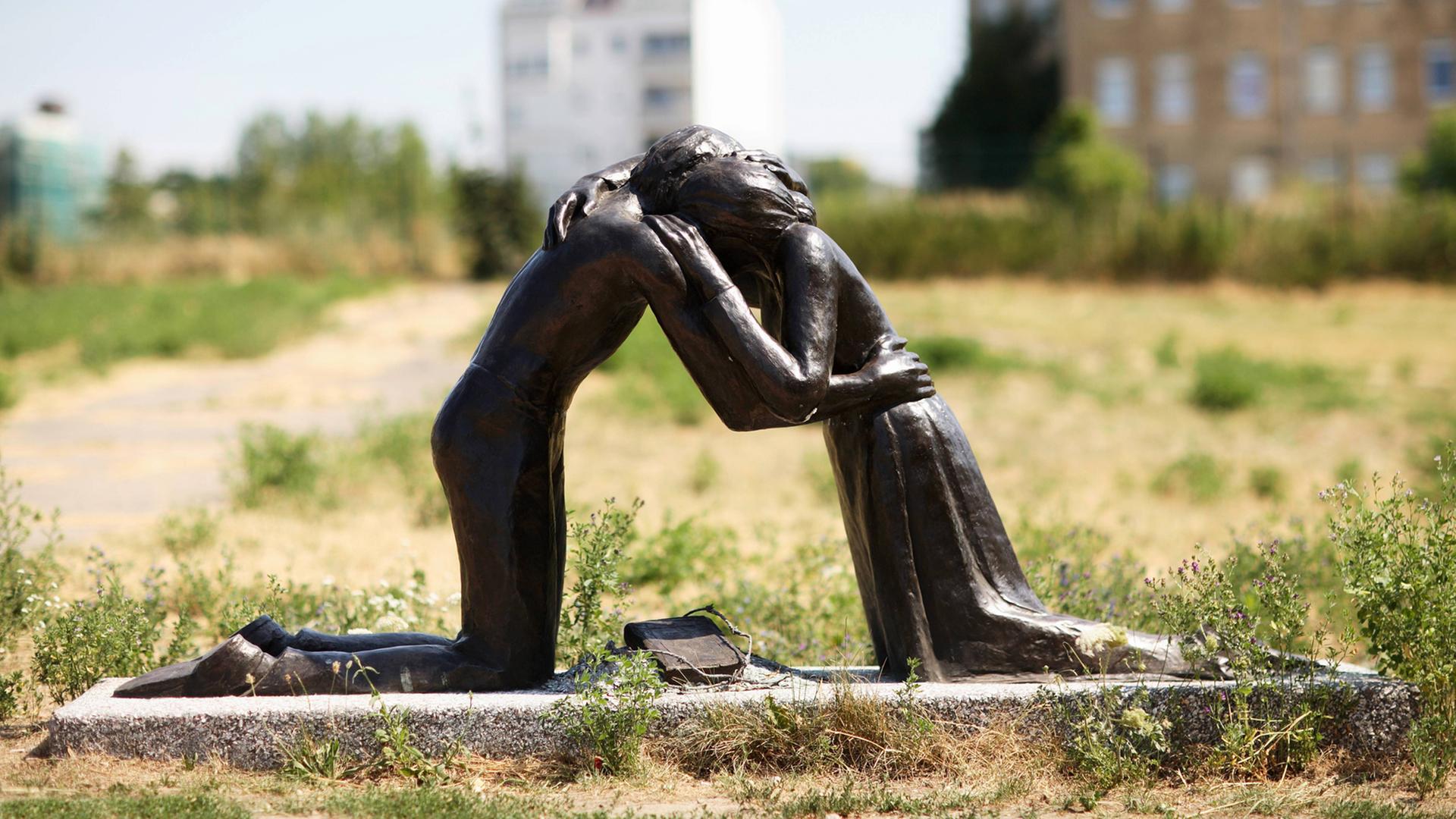 Zwei Knieende, Mann und Frau, die sich umarmen - Skulptur "Versöhnung" an der Versöhnungskapelle in der Bernauer Straße in Berlin