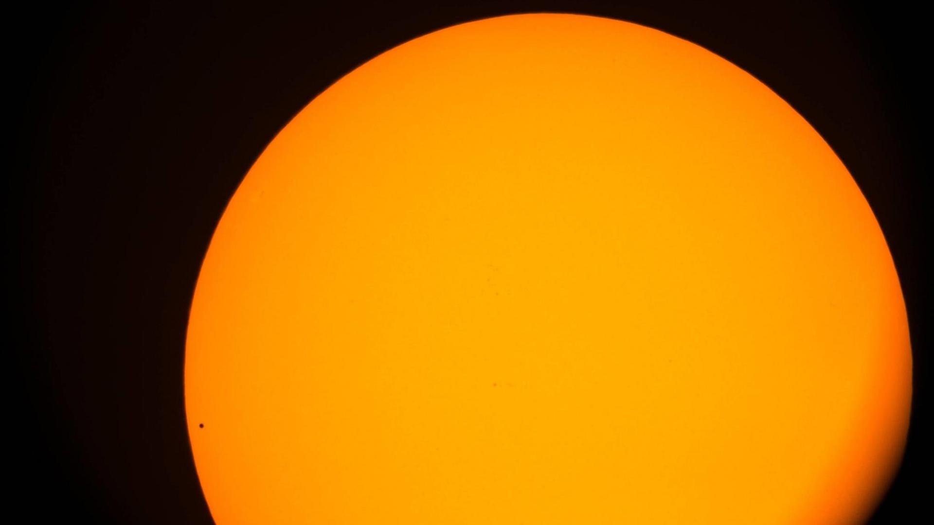 Vor der Sonne in glühendem gelb/organge ist der Merkur nur als kleiner schwarzer Punkt zu erkennen