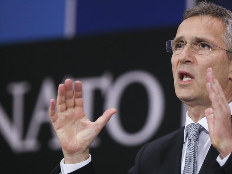 Stoltenberg spricht und gestikuliert im Nato-Presseraum. Im Hintergrund sieht man unscharf den "NATO"-Schriftzug.