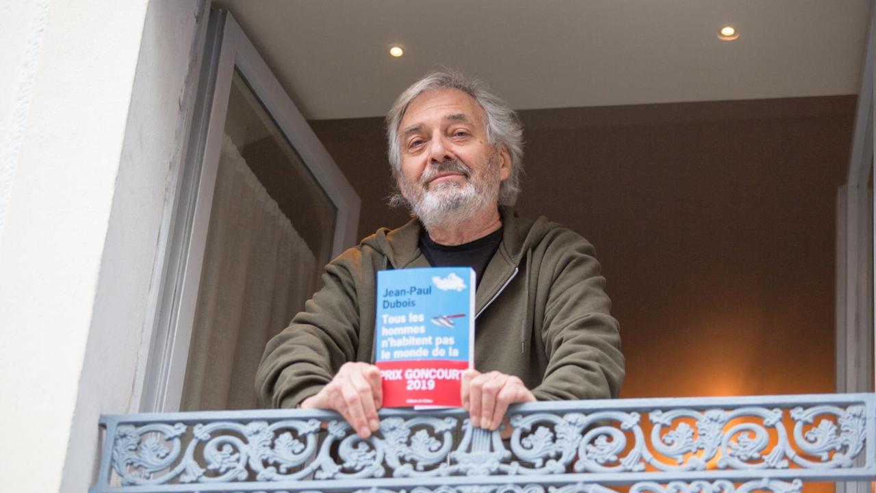 Jean-Paul Dubois steht am Balkon mit seinem Buch. 
